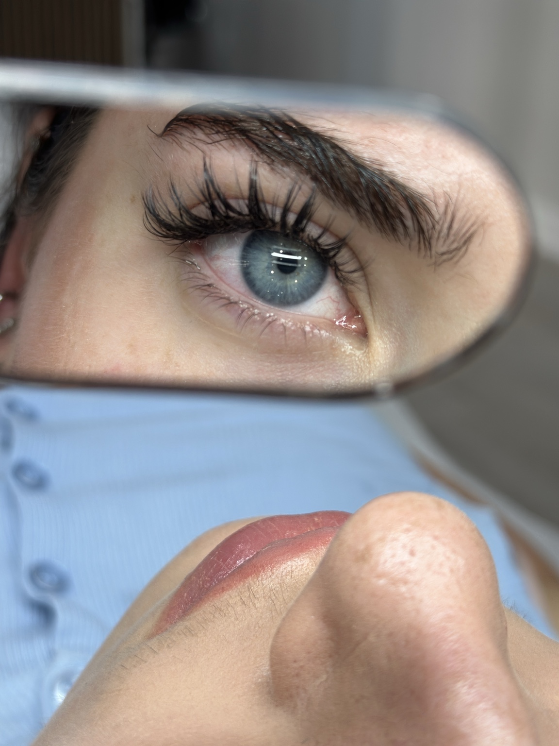 Close-up of eyelash extensions reflected in a handheld mirror